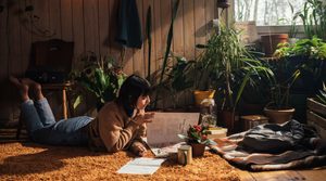 Woman lays on ground with plants reading herbalism book